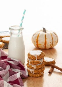 gluten-free-dairy-free-iced-pumpkin-oatmeal-cookies-stacked-by-milk-and-a-mini-pumpkin