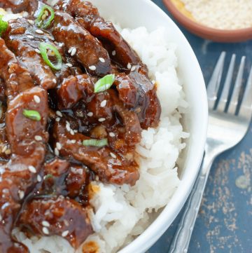 close up of beef teriyaki over rice in a white bowl
