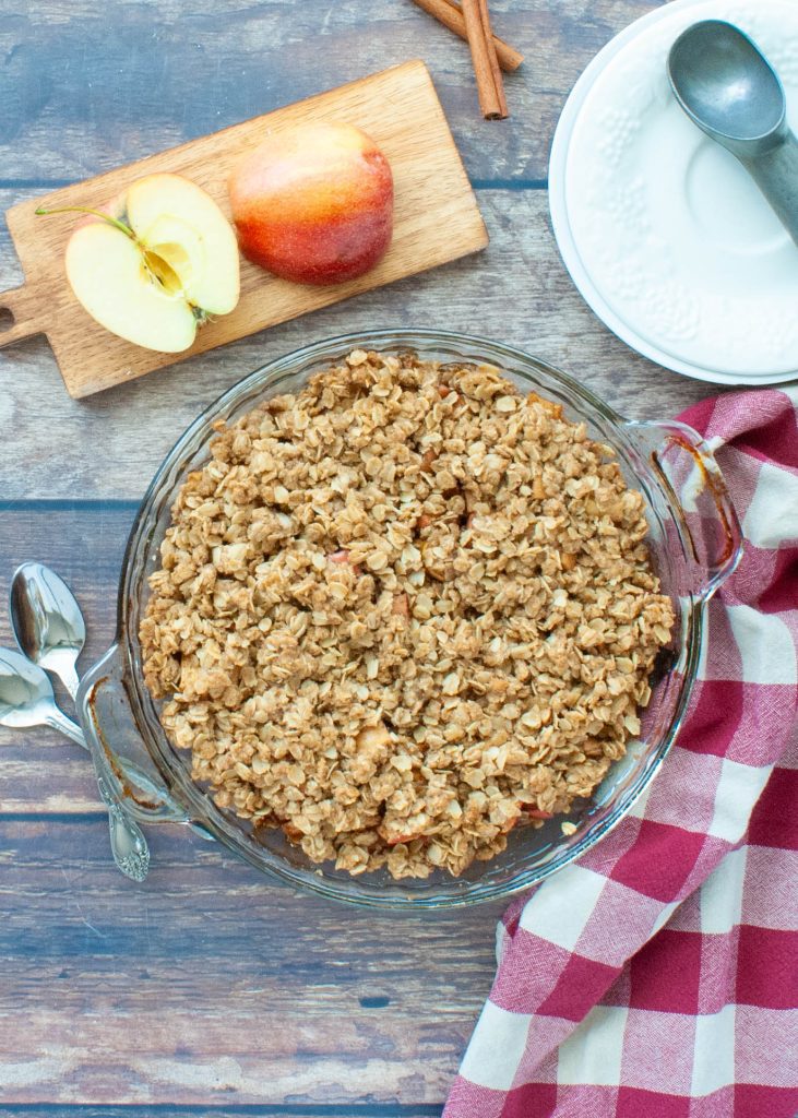 gluten-free-apple-crisp-in-a-glass-pie-plate-with-apples-next-to-it-from-above