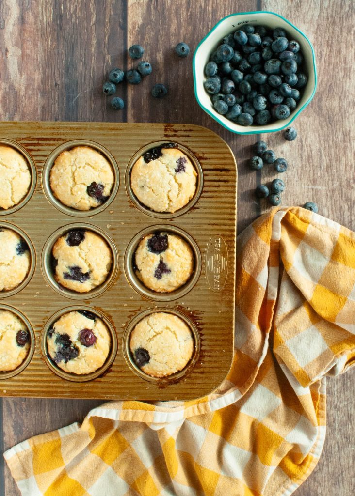 gluten-free-muffins-in-a-tin-shot-overhead-with-blueberries-spilled