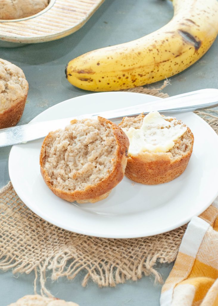 gluten-free-banana-muffin-cut-in-half-with-butter-on-it