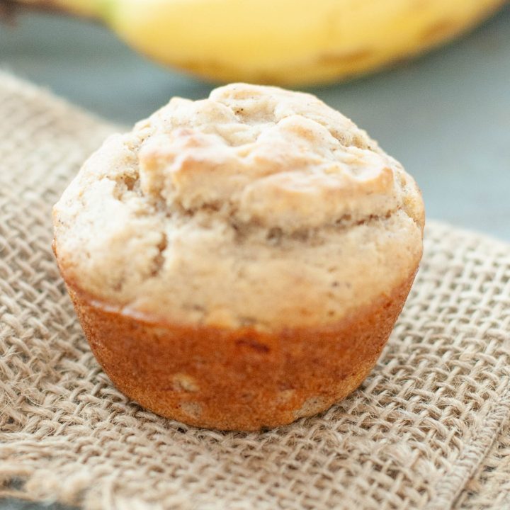 single-gluten-free-banana-muffin-up-close-with-banana-in-the-background