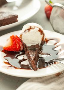 flourless-chocolate-torte-with-ice-cream-and-chocolate-sauce-on-top-with-a-strawberry-next-to-it-straight-on