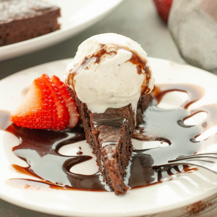 flourless-chocolate-torte-with-ice-cream-and-chocolate-sauce-on-top-with-a-strawberry-next-to-it-straight-on