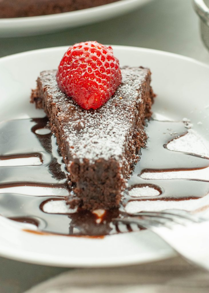 flourless -chocolate-cake-slice-with-chocolate-sauce-and-strawberry-on-top-with-bite-taken
